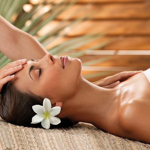 Client Satisfaction Client enjoying a relaxing spa treatment, lying on a mat with a flower in her hair, embodying tranquility and satisfaction